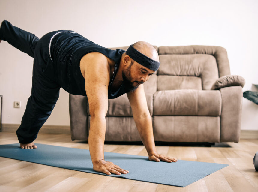 Hombre en esterilla de yoga estirando las piernas y los brazos.