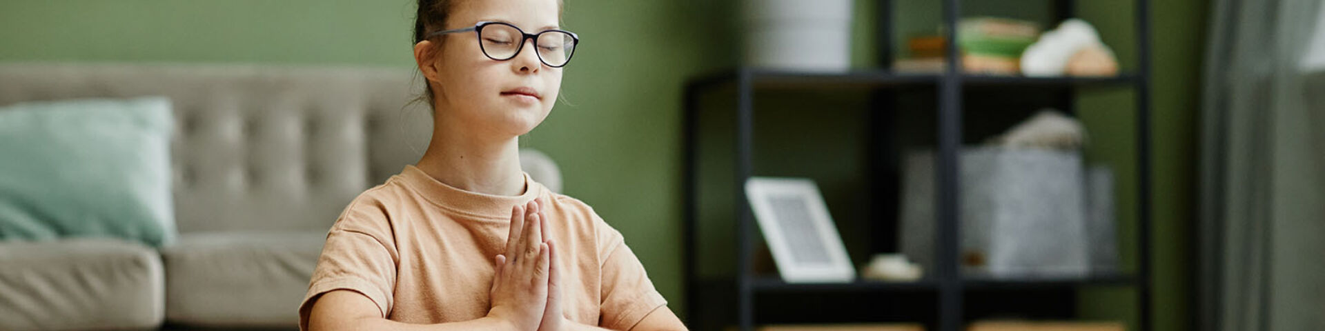 girl sitting on floor with eyes closed and hands in front of her heart