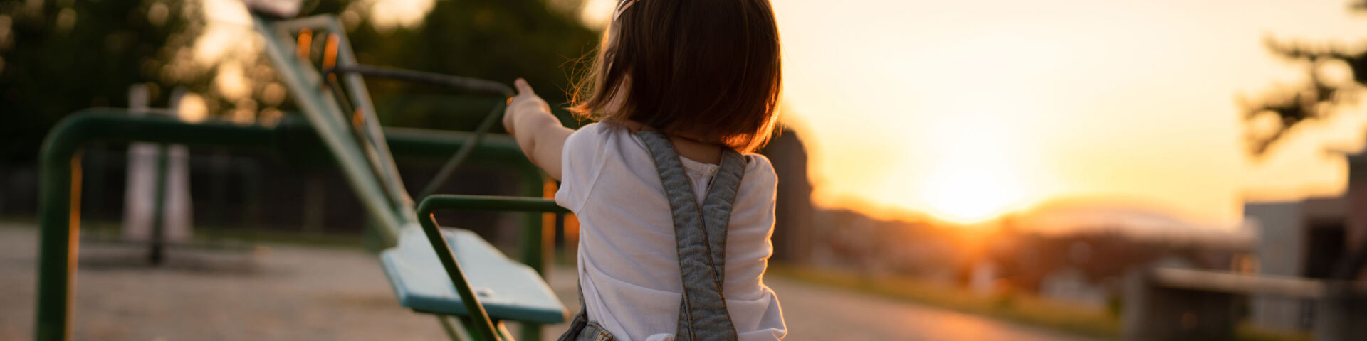 little girl alone on seesaw as sun sets