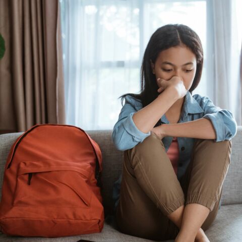 teen girl on couch with knees pulled up under her chin