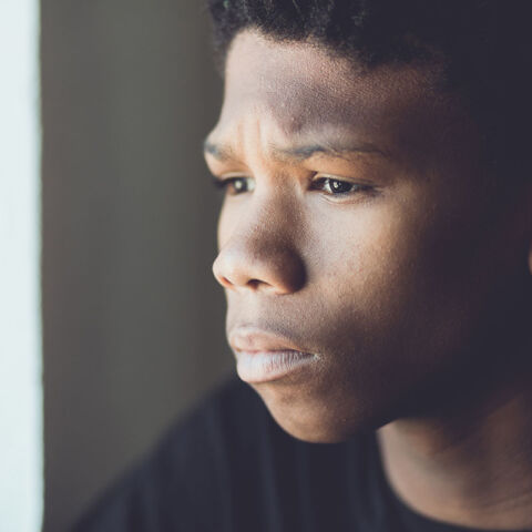 Teen boy staring out window.