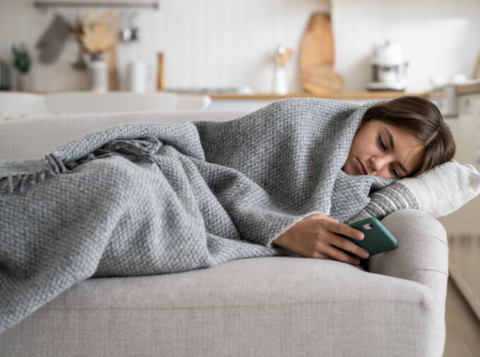 Sad Teen Girl Wrapped in Blanket Looking At Phone