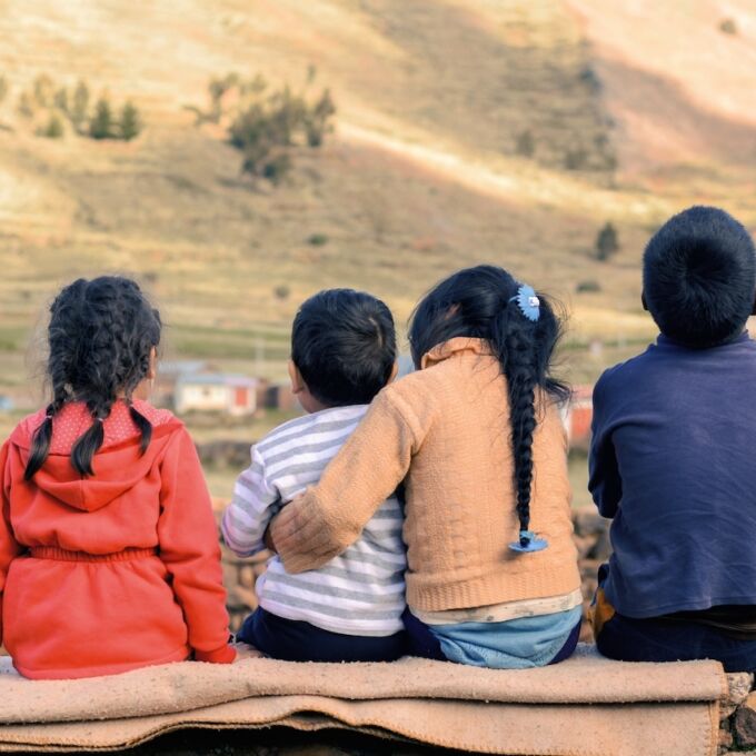 Vista desde atrás de un grupo de niños pequeños con cabello oscuro.