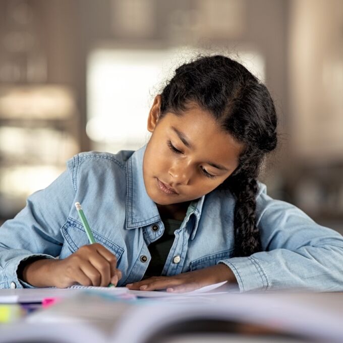 Adolescente nativa americana escribiendo en cuaderno.